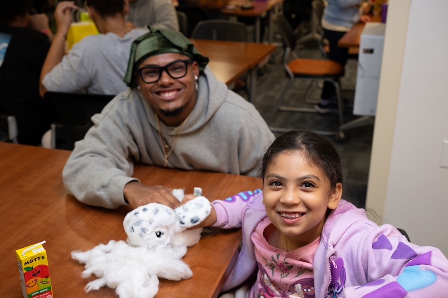 A Southern student and young girl smile together at a Sibling Night activity