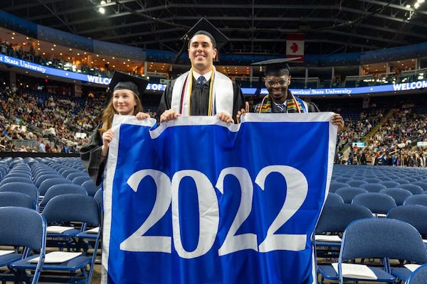 Graduates at commencement holding 2022 sign