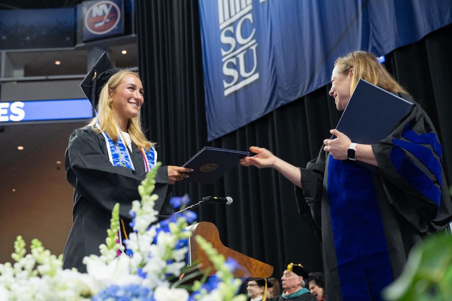 Student receiving diploma jacket on stage